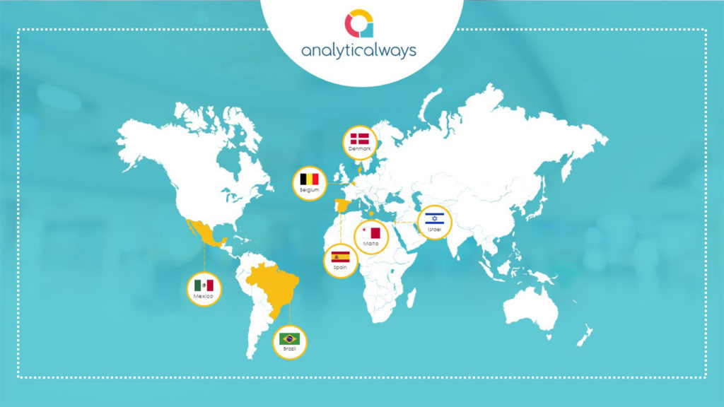 A pitch deck slide with a world map highlighting various countries with flags, including Mexico, Brazil, Belgium, Denmark, Spain, Morocco, and Japan. The “Analyticalways” logo is prominently displayed at the top center of the light blue background. This map is an analytic representation of global diversity.